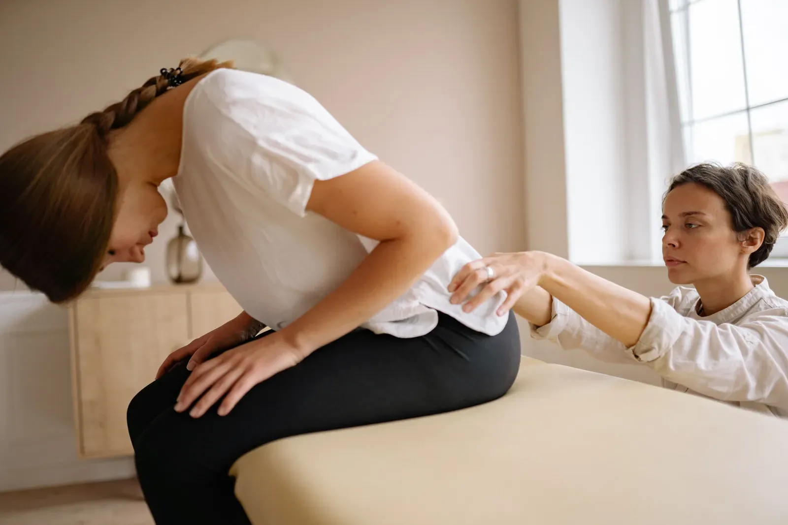 Ostéopathe posant les mains sur le bas du dos d'une patiente